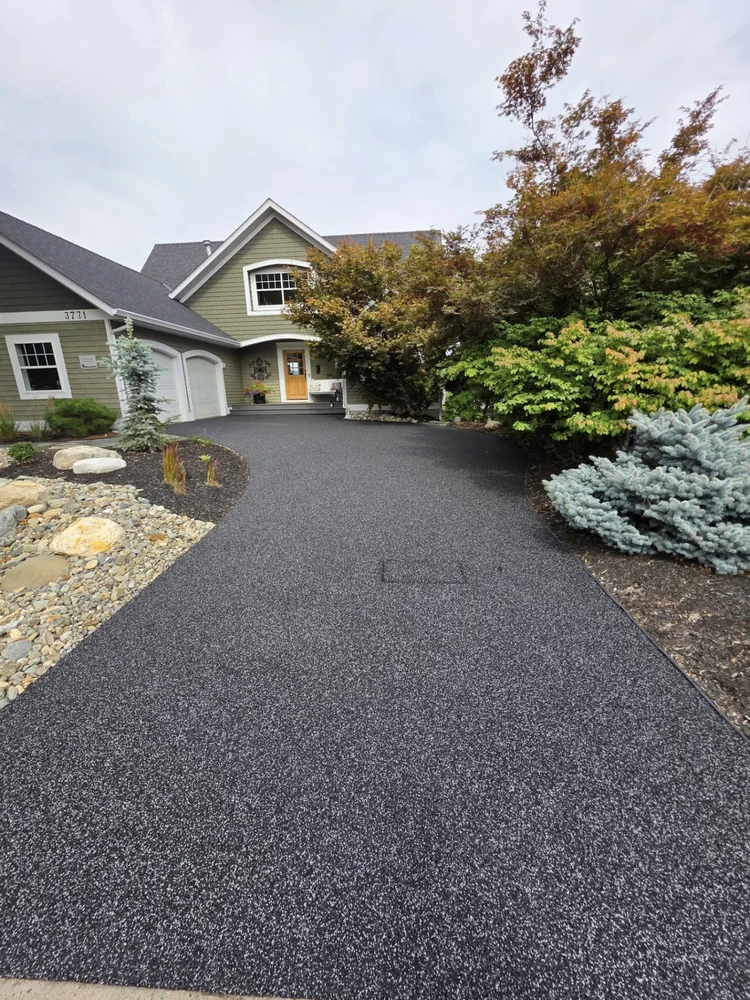 Curved black blend rubber driveway with landscaping